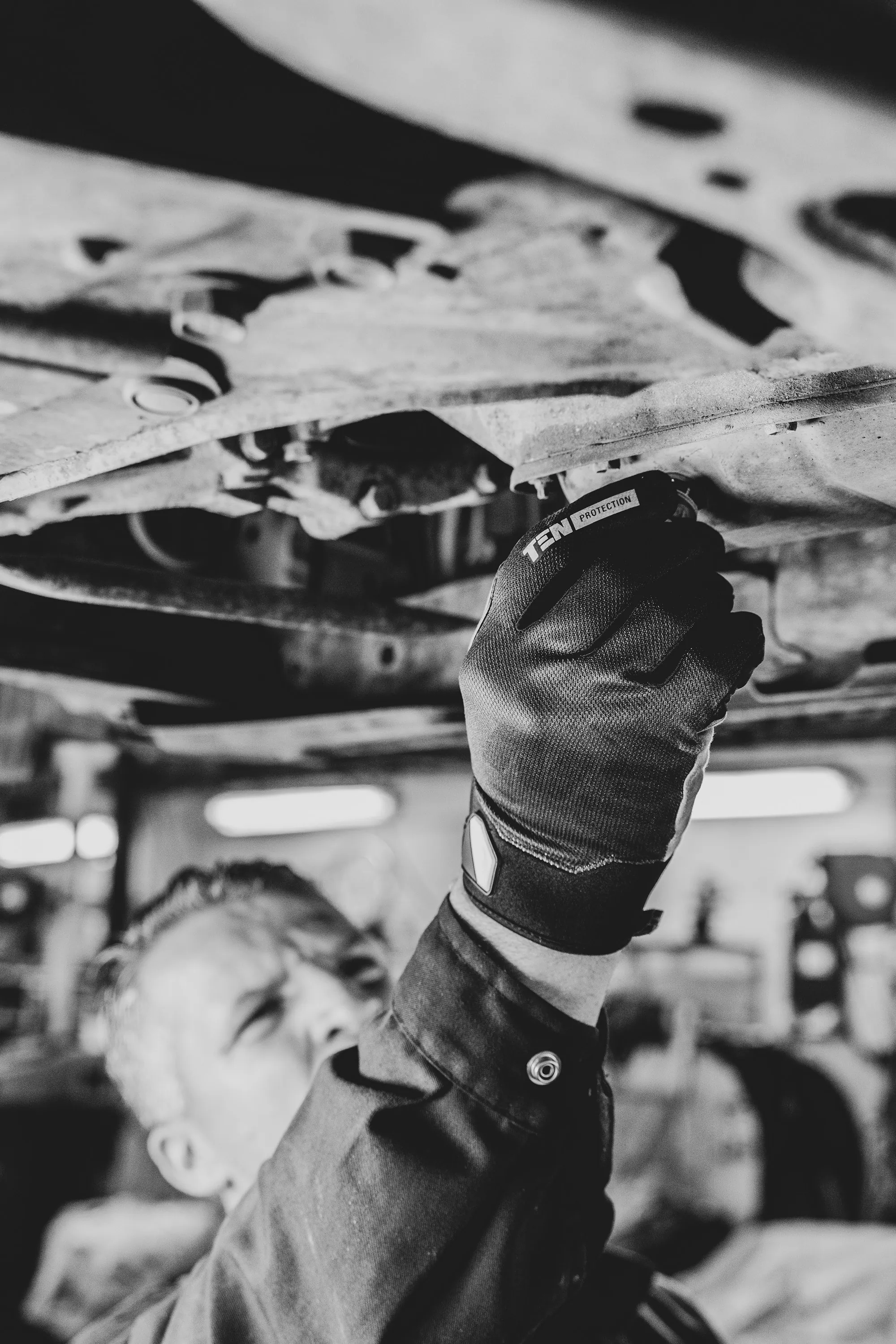 Mechanic in gloves working beneath a raised vehicle
