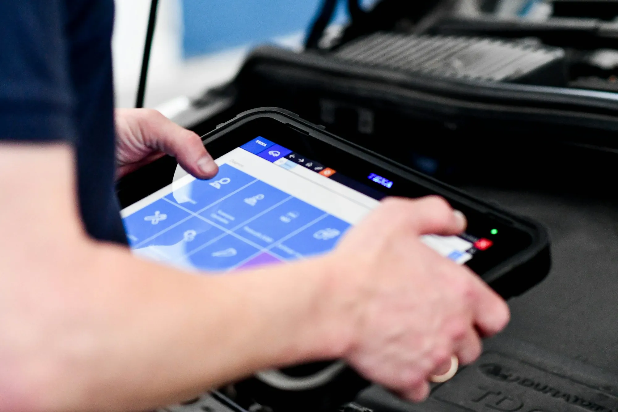 Technician holding a diagnostic tablet near a vehicle