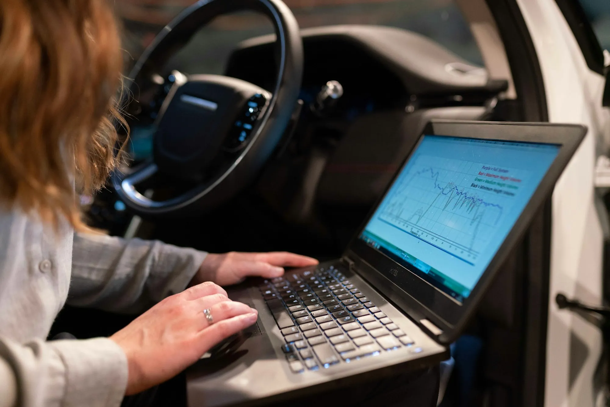 Person using a laptop inside a vehicle's cabin