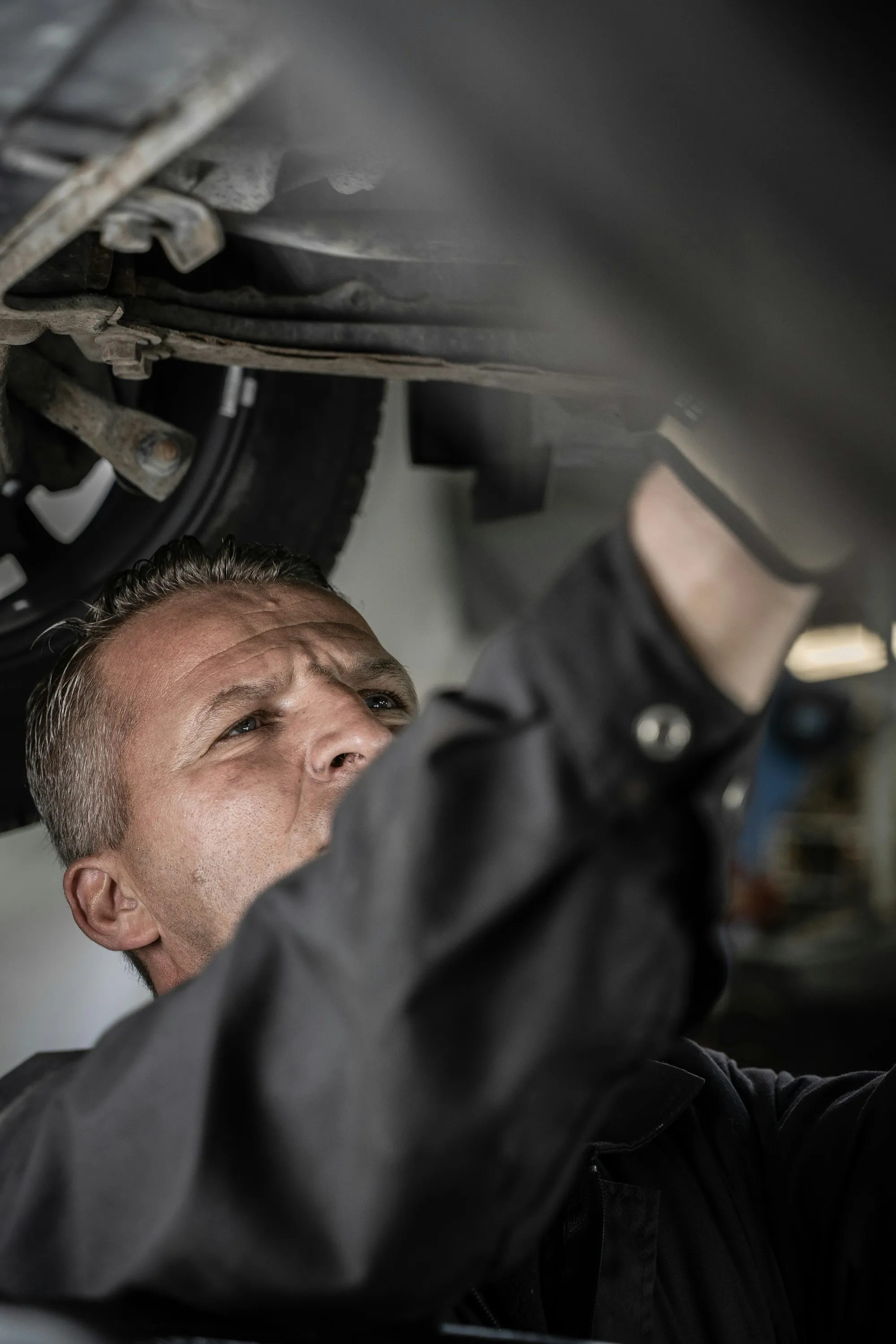 Mechanic looking up at the underside of a raised vehicle